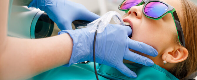 child with teal bib and sunglasses getting a dental x-ray
