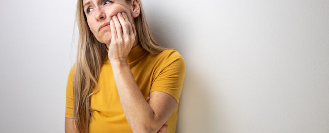 Women in yellow shirt holding mouth