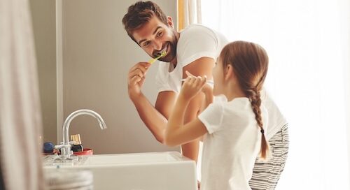 Dad and Daughter Brushing Teeth Together in Bathroom