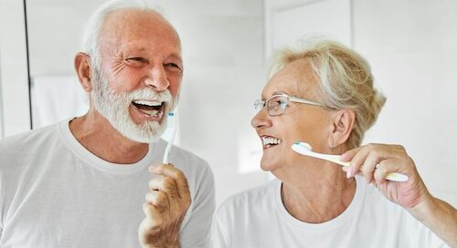 Elderly Couple Brushing Their Teeth in Mirror