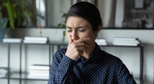Woman Feeling Sick Sneezing in Hand