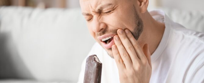 Man with sensitive teeth in pain after eating an ice cream bar