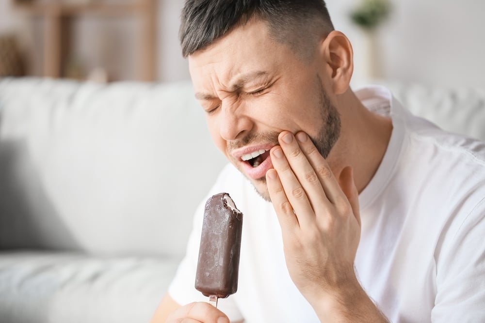 Man with sensitive teeth in pain after eating an ice cream bar