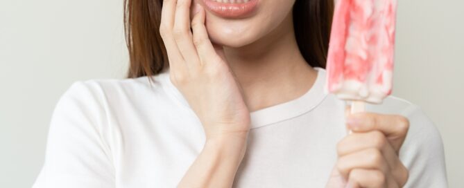 woman suffering from sensitive teeth after eating a popsicle.