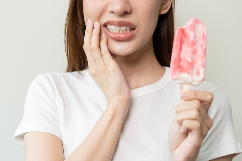 woman suffering from sensitive teeth after eating a popsicle.